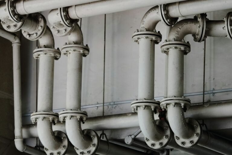 Painted mechanical piping and bolted flanges along a utility room wall