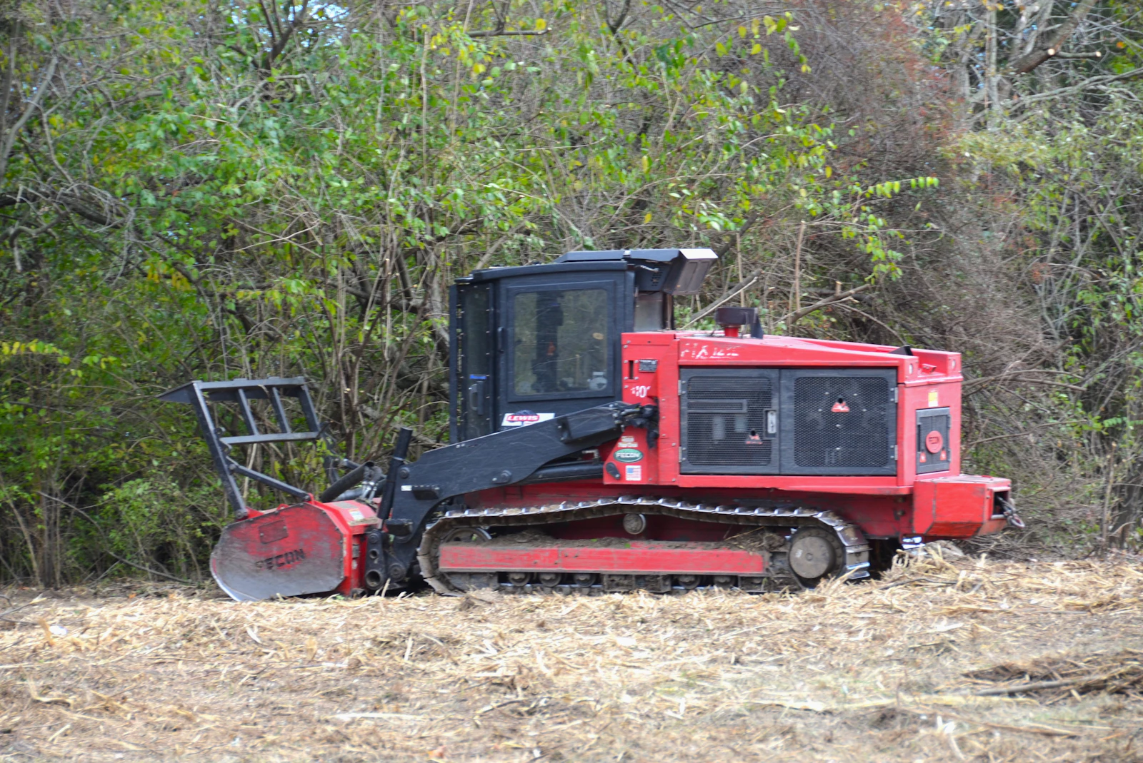 Fecon tracked forestry mulcher Red Fecon tracked forestry mulcher with front-mounted mulching head in a wooded clearing