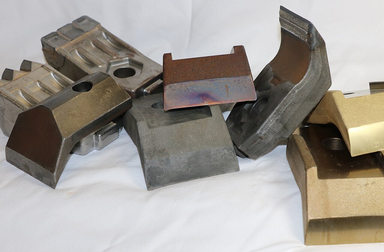 Different forestry mulcher blades and hammers laid out for comparison