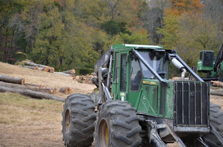 John Deere 648H wheeled logging skidder in a clearing with felled timber