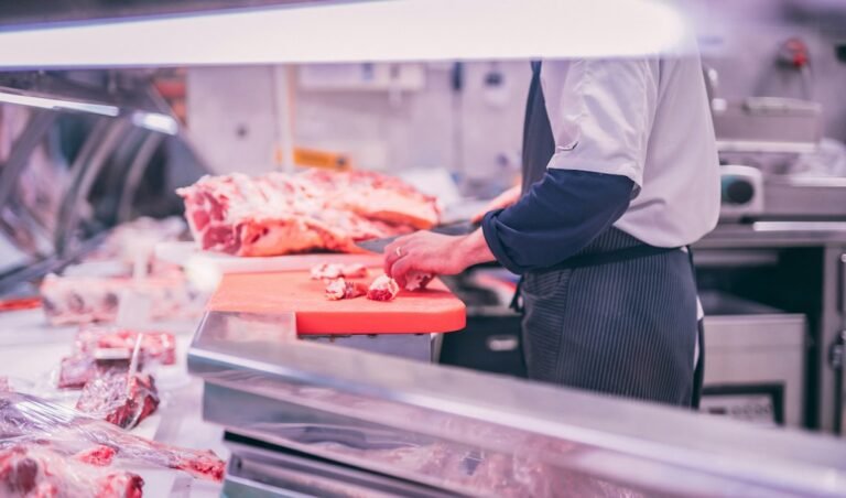 Worker slicing raw meat at a processing station